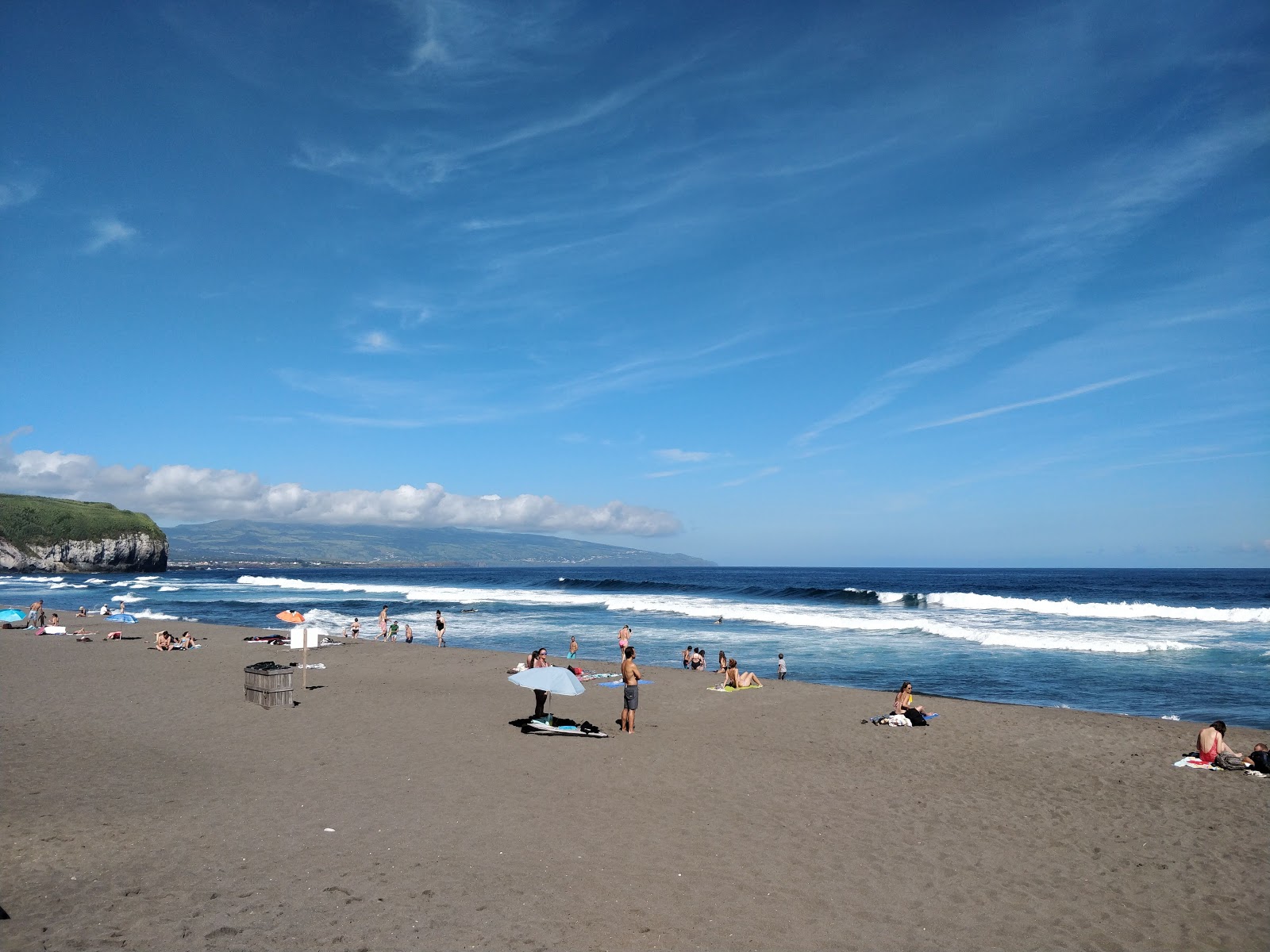 Praia de Santa Bárbara, com areia escura, banhistas e ondas, na Ribeira Grande, São Miguel